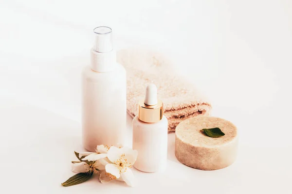 Kozmetikai szappan, szérum és tonik flakon fehér, üres csomagolásban jázminvirággal, fehér háttérrel, fénymásoló felülettel — Stock Fotó