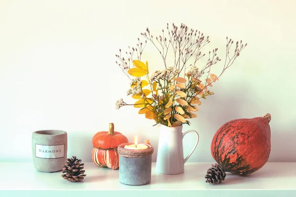 Podzimní aranžmá s dýní, svíčkami, kornouty a žlutými listy ve váze — Stock fotografie