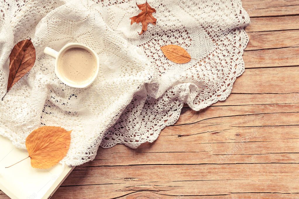 Cup of cappuccino on a tray, knitted napkin, dried leaves. Wooden background, autumn concept. Top view, flat lay, copy space.