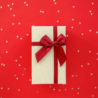 Kırmızı arka planda fiyonklu bir kutuda konfeti. Üst manzara, düz uzanma.