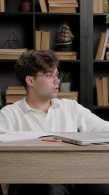 Öğrenci çalışmak ve sınavlara ve sınavlara hazırlanmak için havasında değil. Ofis masasında oturan gözlüklü çocuk üniversiteye başlamak istemiyor. Öğrenci derslerden sıkıldı