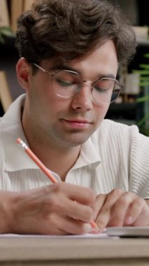 Yakışıklı otantik bir öğrencinin portresi şık bir ofiste, evde dizüstü bilgisayar kullanarak ders çalışıyor ve notlar alıyor. Çocuk teknolojilerin yardımıyla internete girip internetten öğrenim görüyor.