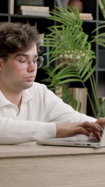 Genç pazarlama ve hedef belirleme uzmanı ofiste uzaktan çalışıyor. Dizüstü bilgisayarda yazan ve her yerden online olarak görevlerini tamamlayan bir çocuk.