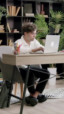 Focused and concentrated student preparing for classes in a modern library. Boy searching information on laptop on internet to do a project at college. Concept of studies, students, classes, college