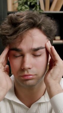 Yorgun esmer öğrenci parmaklarıyla şakaklarına masaj yapıyor. Baş ağrısı çekiyor. Çok fazla öğrenme ve çalışmadan yorgun düşüyor. Kendini adamış öğrenciler ve sürekli öğrenme kavramı