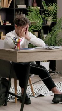 Tired and exhausted student with no mood to study. Boy rubs his eyes with his hands from pain from sitting in front of the laptop for a long time. Concept of students, pupils, school, lessons, exams