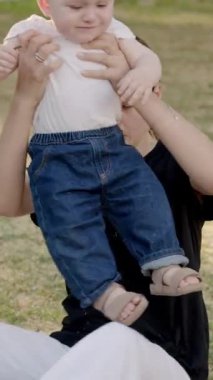 Bebek çimen ve yapraklarla meşgul, canlı bir açık havada dokuları ve renkleri keşfediyor, merakın ve duyusal keşfin özünü yakalıyor.