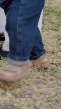 Bebek çimen ve yapraklarla meşgul, canlı bir açık havada dokuları ve renkleri keşfediyor, merakın ve duyusal keşfin özünü yakalıyor.