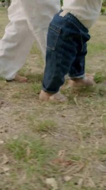 Bebek çimen ve yapraklarla meşgul, canlı bir açık havada dokuları ve renkleri keşfediyor, merakın ve duyusal keşfin özünü yakalıyor.