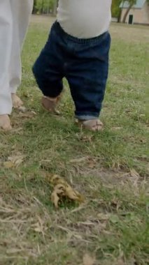 Bebek çimen ve yapraklarla meşgul, canlı bir açık havada dokuları ve renkleri keşfediyor, merakın ve duyusal keşfin özünü yakalıyor.