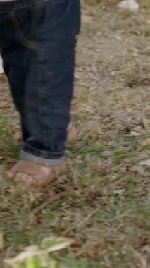 Bebek çimen ve yapraklarla meşgul, canlı bir açık havada dokuları ve renkleri keşfediyor, merakın ve duyusal keşfin özünü yakalıyor.