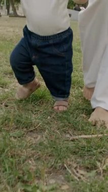 Bebek çimen ve yapraklarla meşgul, canlı bir açık havada dokuları ve renkleri keşfediyor, merakın ve duyusal keşfin özünü yakalıyor.