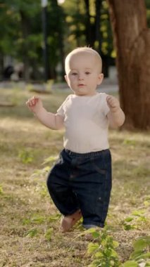 Bebek çimen ve yapraklarla meşgul, canlı bir açık havada dokuları ve renkleri keşfediyor, merakın ve duyusal keşfin özünü yakalıyor.