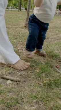 Bebek çimen ve yapraklarla meşgul, canlı bir açık havada dokuları ve renkleri keşfediyor, merakın ve duyusal keşfin özünü yakalıyor.