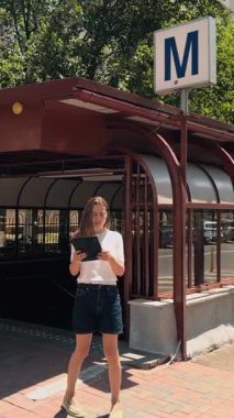 Dişi gezgin metro girişinde akıllı telefonla iletişim kurar, sonra istasyona doğru yürür, yeni bir şehir ortamında gezinmenin yolculuğunu betimler.