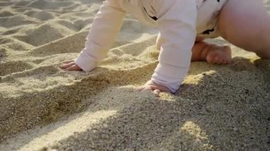Baby engages with soft sand on the beach, feeling the warm grains while exploring the surroundings, capturing the essence of playful childhood moments