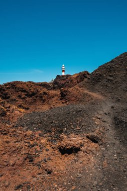 Deniz feneri bir dağın arkasına gösteriliyor