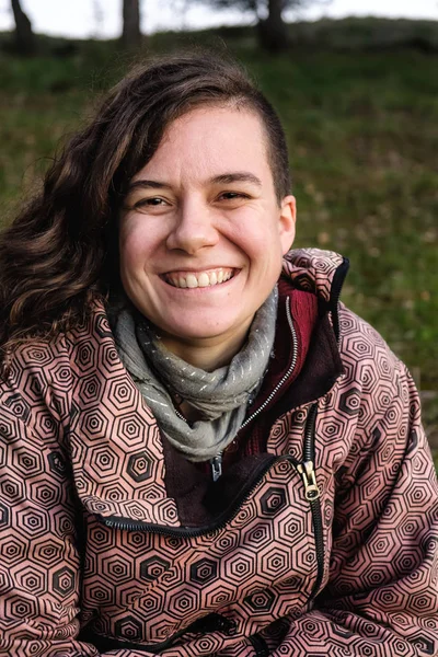 Genç bir kadın kameraya bakıp gülümsüyor.