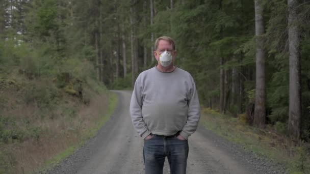 Mężczyzna w masce N95 w lesie podczas pandemii COVID, zoom out shot — Wideo stockowe