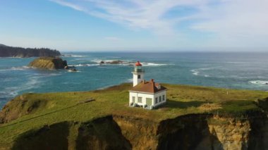 Oregon 'da Cape Arago Deniz Feneri ve arka planda Shore Acres