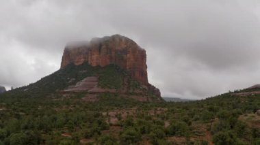 Hava aracı Sedona 'da bulutlu bir günde büyük bir kızıl kayaya yaklaşıyor.