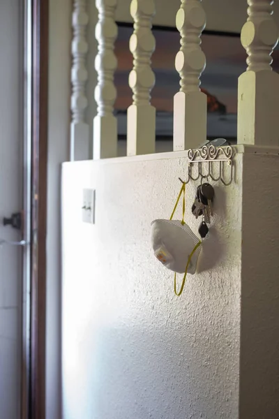 Car keys and face mask hang on a key hanger rack during coronavirus outbreak