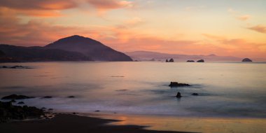 Oregon 'daki Port Orford' un deniz manzarası ve gün batımında Humbug Dağı.