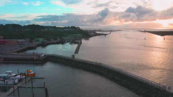 Drone voa sobre docas e marina em Bandon, Oregon, EUA durante o pôr do sol nublado. — Vídeo de Stock