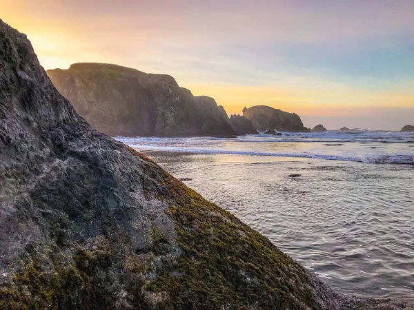 Roca musgosa en primer plano con pilas de mar y el océano en el fondo. — Foto de Stock