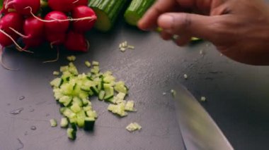 Vejetaryen yemeği için salatalık doğrayan ellere yakın çekim.