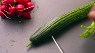 Yakından bakan kişi, vejetaryen yemeği için salatalık doğruyor.