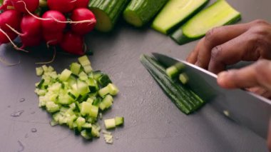 Vejetaryen yemeği için salatalık doğrayan ellere yakın çekim.