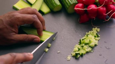 Vejetaryen yemeği için salatalık doğrayan ellere yakın çekim.