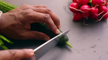 Yakından bakan kişi, vejetaryen yemeği için salatalık doğruyor.