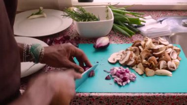 Mutfakta soğan ve mantar doğrayan şefin yakın çekimi.