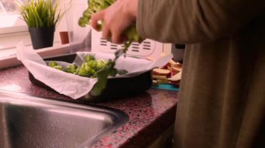 Fırın tepsisiyle doğranmış sebzelerle yemek hazırlayan kişi.