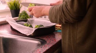 Fırın tepsisiyle doğranmış sebzelerle yemek hazırlayan kişi.