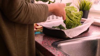 Fırın tepsisiyle doğranmış sebzelerle yemek hazırlayan kişi.