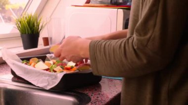 Fırın tepsisiyle doğranmış sebzelerle yemek hazırlayan kişi.