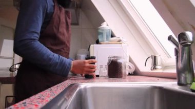 Yetişkinler mutfakta elle kavrulmuş kahve çekirdeklerini öğütüyor.