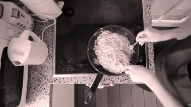 Kadın, mutfakta elektrikli fırında makarna yapıyor. Siyah beyaz. 