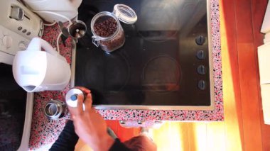 Elektrikli sobanın üstünde moka demliği olan espresso kahvesi hazırlayan kişinin üst görüntüsü.