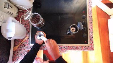 Kahve çekirdeklerini öğüten ve kahve demliğiyle espresso hazırlayan biri.