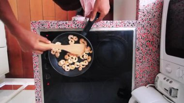 Top view chef frying shrimps on electric stove