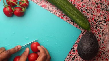Slicing tomatoes and cucumber on cutting board