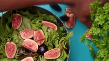hands of male chef preparing healthy green salad with figs in kitchen