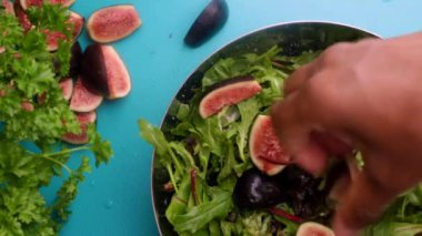 hands of male chef preparing healthy green salad with figs in kitchen