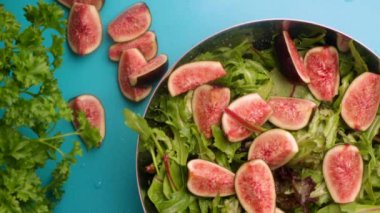 hands of male chef preparing healthy green salad with figs and walnuts in kitchen