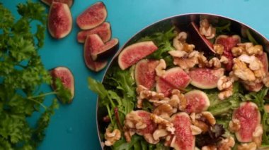 hands of male chef preparing healthy green salad with figs and walnuts in kitchen