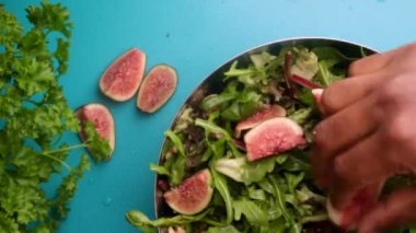 hands of male chef preparing healthy green salad with figs and walnuts in kitchen